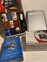 Photo showing boxed custom shaped car cushion, white drawing tablet, boxed hands-free car kit, and boxed Roxio Creator Pro 10 software.