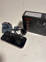 Photo of Term HDMI switch, 911 alert device, charging dock, and power adapter next to a box for the portable PA system.