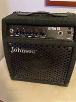 Front view of Johnson Reptone 15B guitar amplifier showing control panel, grille with Johnson logo, power switch, and headphone output.