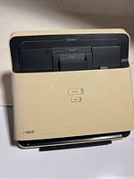 Front view of the Neat desktop scanner showing input slots labeled for documents, receipts, and cards, with SCAN and PDF buttons visible on the front panel.