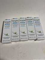 Five boxed bottles of Simple Hydrating Booster arranged in a row showing front