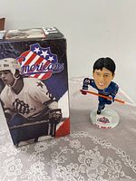 Bobblehead figure with original box, showing front and side details of the item and packaging.