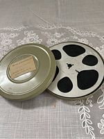 Metal reel canister with open lid showing the metal 8mm film reel inside.