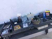 Wide view of table with various tools including grinder, level, kits, and tool bag