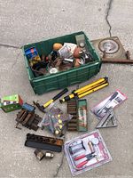 Full view of all items including green bin filled with miscellaneous tools and spread of additional tools and sockets outside the bin.