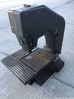 Front and top angle showing the band saw blade opening and ribbed metal work surface with signs of rust and use.