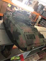 Large G.I. Joe toy tank in camouflage colors showing top and side details including gun turrets and tracks.