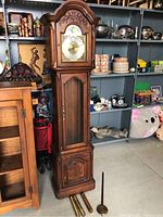 Full view of the tall wooden grandfather clock with pendulum and weights laid in front.