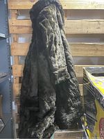 Full length heavy fur coat hanging, showing the dark brown textured fur exterior.