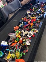 Overview of various toys spread out on a black surface including action figures and small toy vehicles.