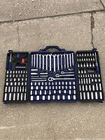 Full view of open blue tool case showing all tools including sockets, ratchets, wrenches, screwdrivers, and bits arranged in designated slots.