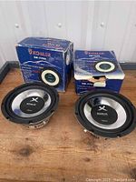 Two Koiiler 8-inch chrome woofers alongside their original boxes on a wooden surface.