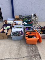 Overview of multiple plastic bins filled with assorted Halloween decorations and two life-size skeleton props
