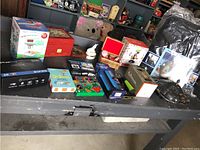 View of assorted boxed items including media players, light bars, and decorative boxes on a grey table.