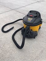 Shop Vac wet/dry vacuum cleaner front view showing yellow tank, black lid and hose attached.