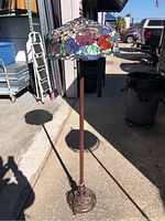 Full view of Tiffany style floor lamp showing stained glass floral shade and metal base.