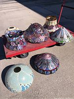 Overview of seven lampshades on red cart and ground