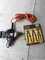 Photo showing corded impact drill with attached orange extension cord and boxed set of three Craftsman Robo-Grip pliers.
