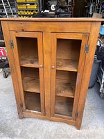 Front view of the 4-foot tall wooden cabinet with two glass paneled doors and wooden shelves inside. Shows overall condition and structure.