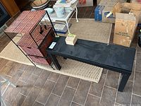 View of black IKEA bench, wicker and metal storage unit, and matching wall shelf with hardware and some boxes in background