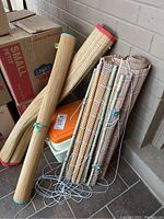 Two sets of bamboo blinds, two rolled woven beach mats, and a Coleman cooler grouped together showing general condition and sizes