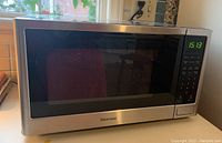 Closed Kenmore microwave oven stainless steel front with digital display showing time.