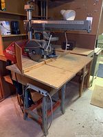 Full view of radial arm saw on wooden tabletop and steel stand
