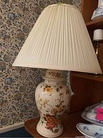 Ceramic table lamp with a cream base decorated with floral patterns and pleated fabric shade