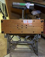 Front view of the Black & Decker workbench showing wooden top with holes and metal frame with logo.