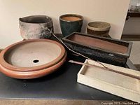 All six pottery pots arranged on table showing variety of shapes and sizes.