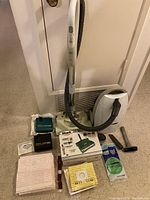 Kenmore Progressive HEPA canister vacuum with hose, Shark vacuum box, multiple bags including Kenmore vacuum bags, and vacuum attachments arranged on carpet.
