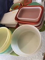 Various sizes of Tupperware bowls and containers stacked, showing variety and colors.