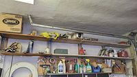 Wide view of shelves with various chemicals, tools and hardware, including paint thinner, spray bottles, screwdrivers, and small containers.