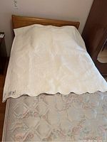 Coverlet spread over bed showing full size and scalloped edges.