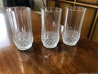 Three clear cut crystal highball glasses on wood table showing pattern detail