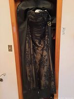 Full view of custom ladies long dress with corset hanging in garment bag