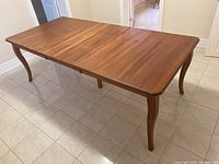 Wood dining table extended with leaf in place, showing full length and wood grain finish