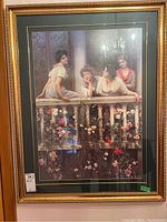 Full view of framed print showing four women on a balcony with floral decorations, including stickers and light reflections.