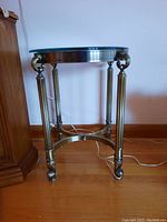 Full front view of the metal base and glass top round side table showing legs and details.