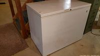 White Sears chest freezer, rectangular shape, visible exterior from side angle showing some wear and dirt marks.