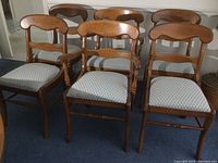Wide view showing all six wooden dining chairs in a room with two captains and four regular chairs.