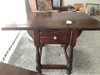 Front view of the vintage wooden Ethan Allen drop side table showing the center drawer with porcelain pull and drop leaves extended.