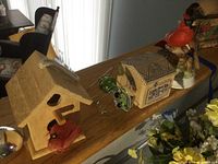 Wooden birdhouse, red cardinal figurine, Gorham musical cardinal figurine, and other assorted decorative items on a table.