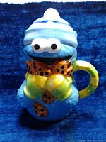 Front view of Cookie Monster ceramic mug holding cookies with the lid on, showing overall design and condition.