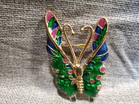 Front view showing the enamel decorated butterfly brooch with green, blue, and pink colors and detailed gold tone antennae.