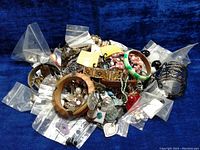Top view of assortment of costume jewelry including bangles, earrings, necklaces with some pieces individually bagged.