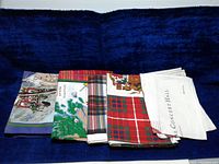 Group photo of 5 vintage unused tea towels with varied prints and tartan patterns.