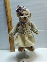 Full body front photo of plush bear in clothes next to ruler showing size around 14 inches tall.