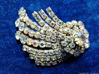 Front view of the vintage Continental rhinestone brooch showing multiple rows of rhinestones fanning out from a circular central cluster with aura borealis effect stones.