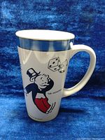 Front side of the vintage Monopoly mug showing Mr. Monopoly with red bag and dice, blue rimmed top